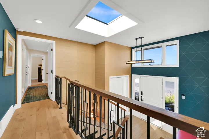 Skylight feature, beautiful LVP flooring, contemporary chandelier, durable metal railing, and geometric accent wall