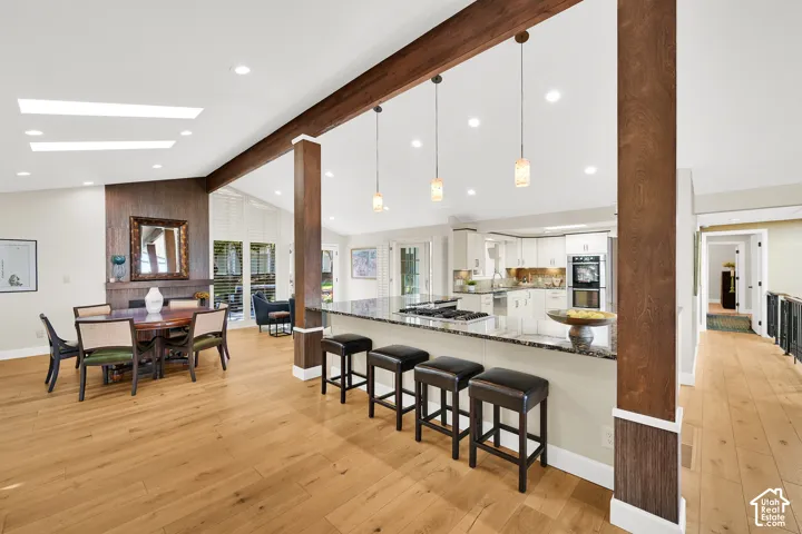 Wood-finish flooring throughout, vaulted ceilings with skylights, exposed wood beams, and a kitchen island with built-in cooktop and bar seating