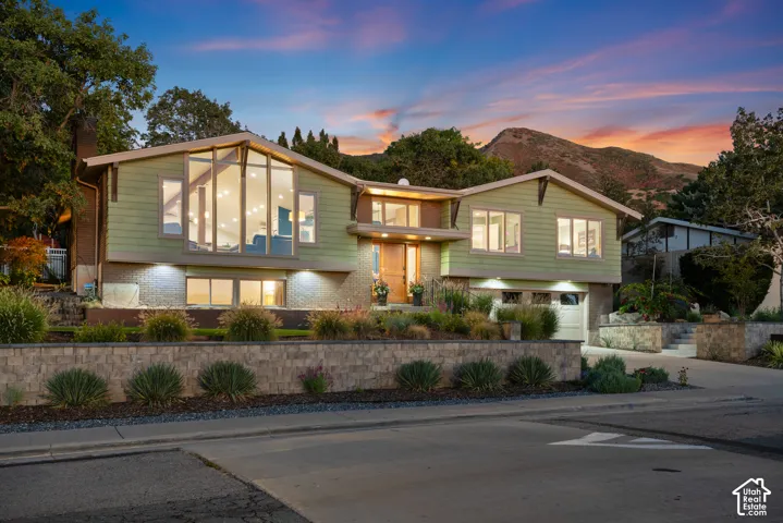 Oak Hills residence featuring a prominent gabled roofline, large picture windows, and a new multi-level stone retaining walls and professionally designed landscape