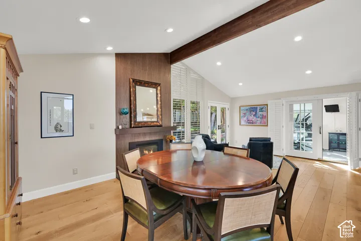 Wood-finish flooring, recessed lighting, vaulted ceiling, built-in fireplace, and double French doors with plantation shutters