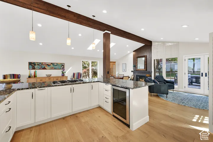 Kitchen with white cabinetry, dark stone countertops, and a built-in beverage cooler
