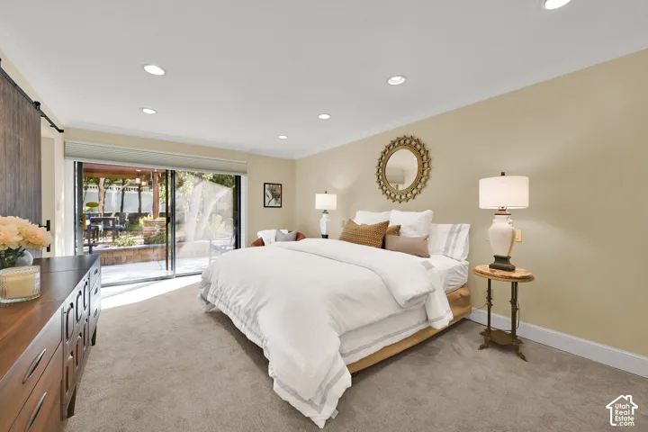 Spacious Master suite that exits to private patio and pergola. Recessed lighting, wood-finish barn door, sliding glass doors, neutral wall color, and light-colored carpeting