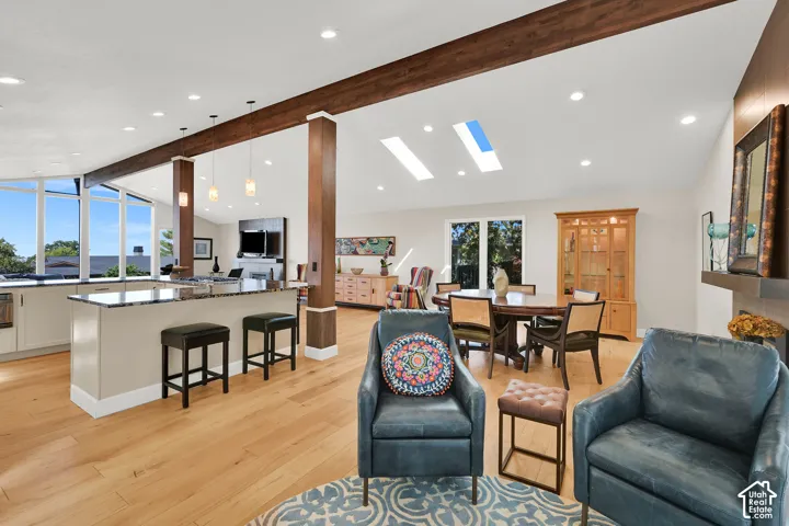Expansive open-concept living area featuring vaulted ceilings, wood-finish beams, and recessed lighting