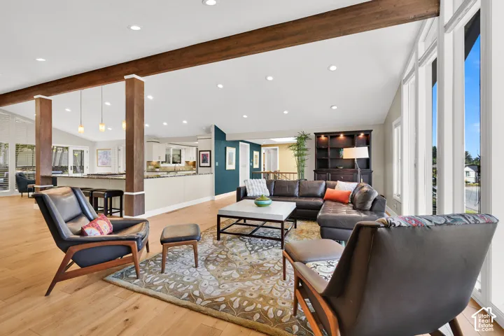 Vaulted ceilings with exposed wood beams, recessed lighting, and expansive windows