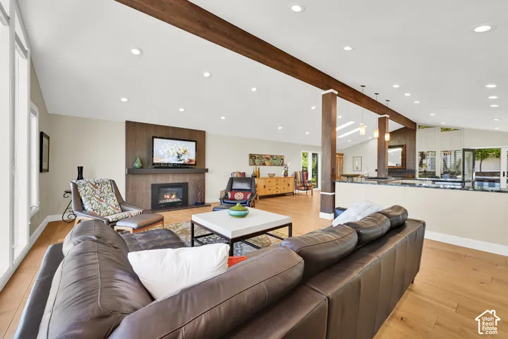 Entertainers dream! Vaulted ceiling with exposed wood-finish beams, recessed lighting, LVP flooring, built-in fireplace with wood-finish surround, and expansive windows with Lake views