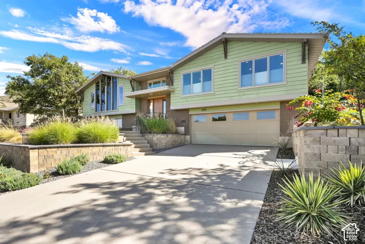 Modern exterior with a two-car garage, and extensive landscape design featuring beautiful perennials throughout and stone retaining walls