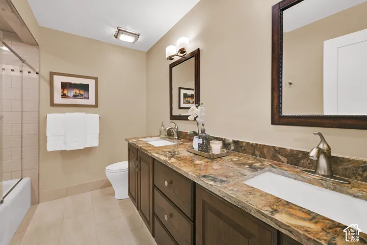 Main Floor Full bath with Dual vanity with undermount sinks, stone countertop, and dark wood-finish cabinetry