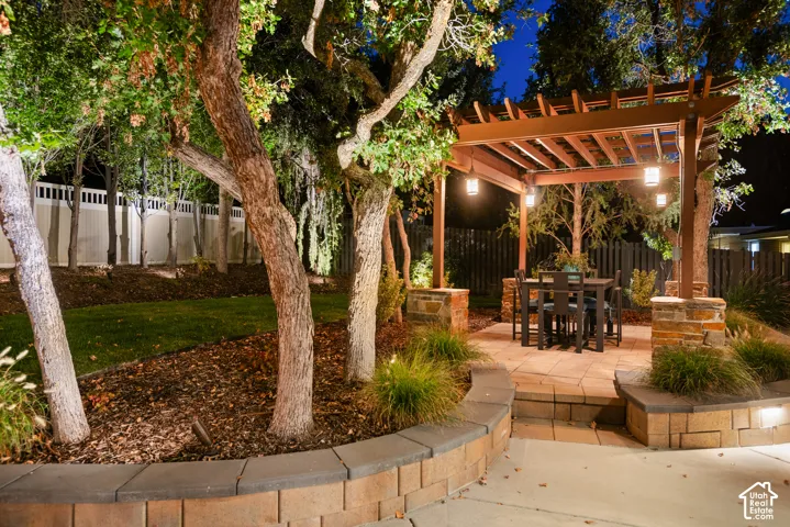 Wood pergola with pendant lighting, paver patio, and stone veneer retaining walls