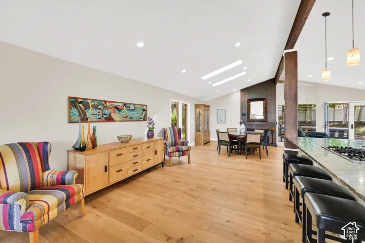 Vaulted ceiling with skylights, wood-finish flooring, recessed lighting, exposed wood beam, and a built-in fireplace