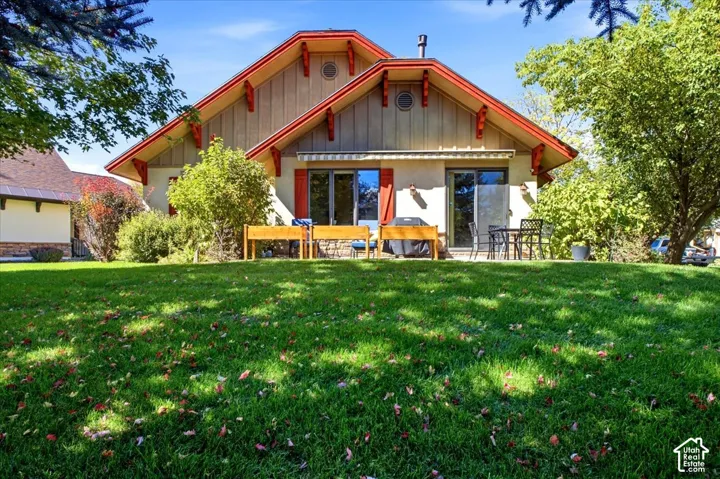 Rear of home featuring an expansive lawn with mature trees