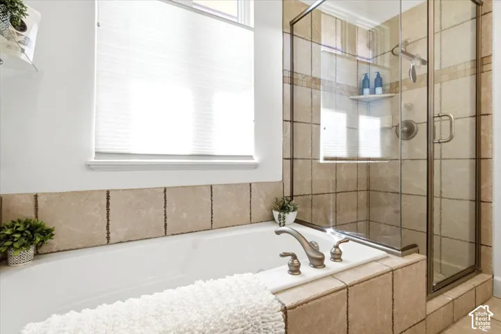 Primary suite bathroom featuring a bathtub and shower