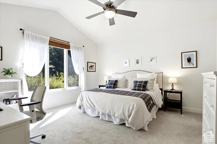 Primary suite featuring a vaulted ceiling, ceiling fan, and a large window