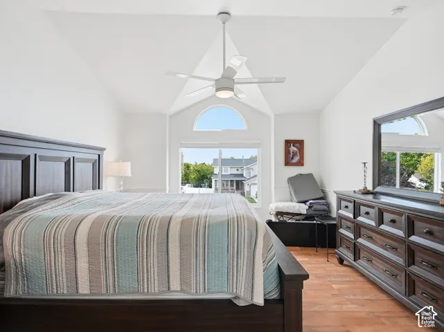 Vaulted ceiling with a ceiling fan, arched transom window, wood-finish flooring, and a dark-finish built-in dresser
