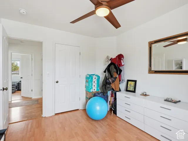 Wood-finish flooring, white walls, and a ceiling fan with integrated lighting