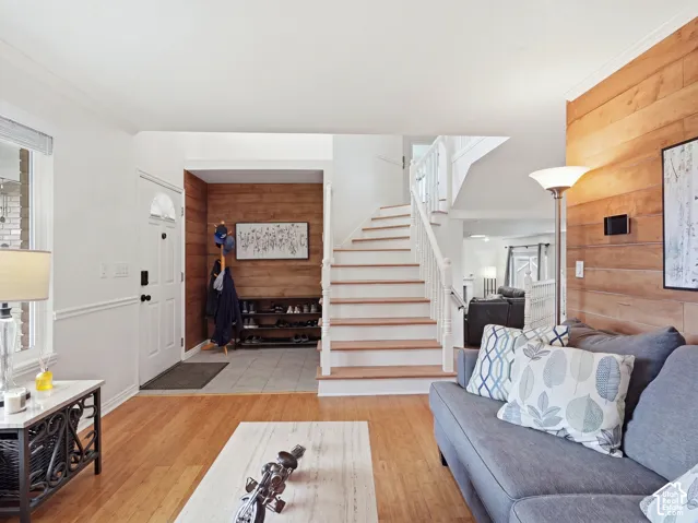 Hardwood-style flooring throughout, white painted trim, white painted doors, wood-paneled accent wall, and a staircase with wood treads and white risers