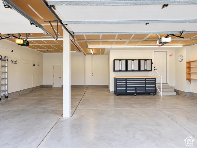 Spacious garage with concrete flooring, multiple overhead lights, and built-in shelving