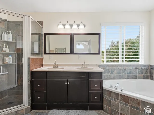 Dual vanity with integrated sinks, dark wood-finish cabinetry, and a corner soaking tub