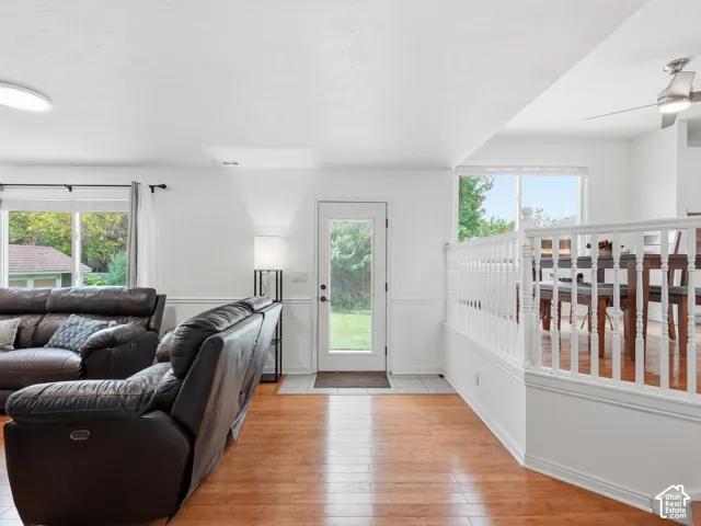 Wood-finish flooring throughout, white wall paneling, glass-paneled exterior door, and a white spindle railing