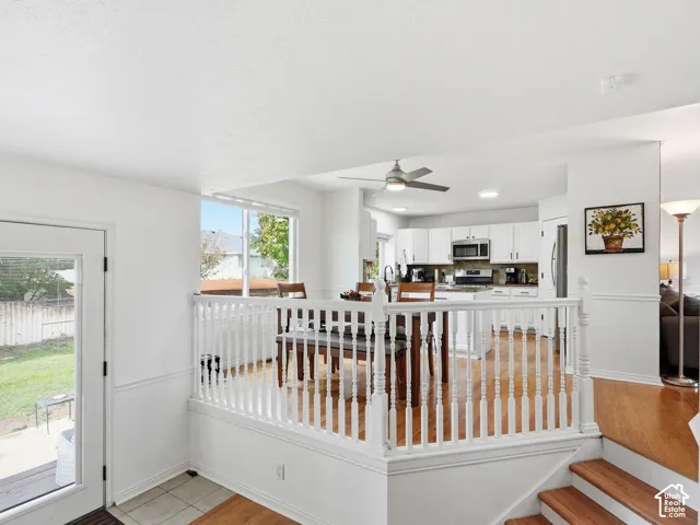 White kitchen cabinetry with stainless steel appliances, wood-finish flooring, recessed lighting, and a ceiling fan