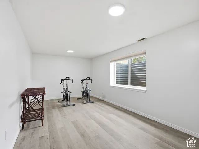 Recessed ceiling lighting, flush-mount ceiling light, light wood-finish flooring, white walls, and a window with a window well