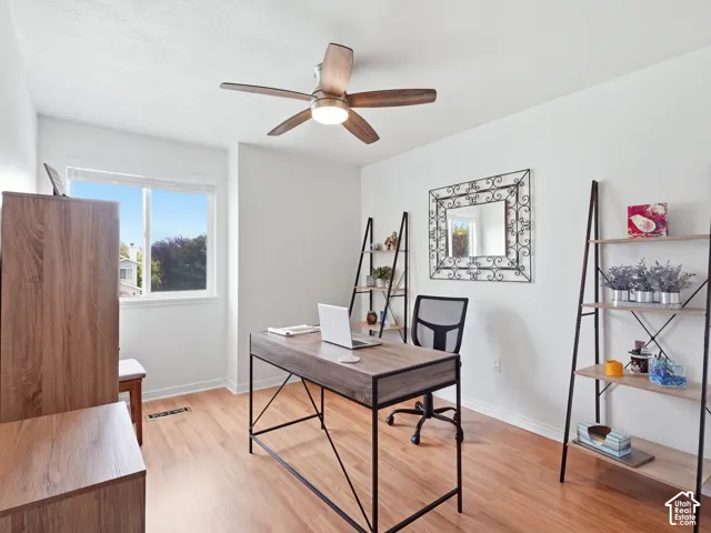 Hardwood-style flooring, white walls, and a ceiling fan with integrated lighting