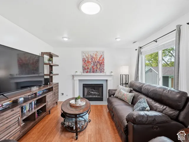 Wood-finish flooring, recessed lighting, and a fireplace with a mantel