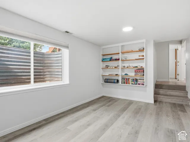 Recessed lighting, built-in shelving, wood-finish flooring, and a window well