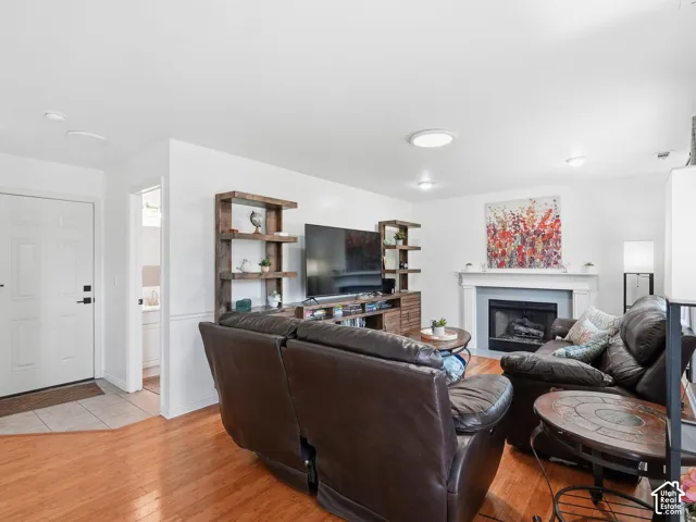 Living area featuring wood-finish flooring, a fireplace with a white mantel, and ceiling-mounted lighting fixtures