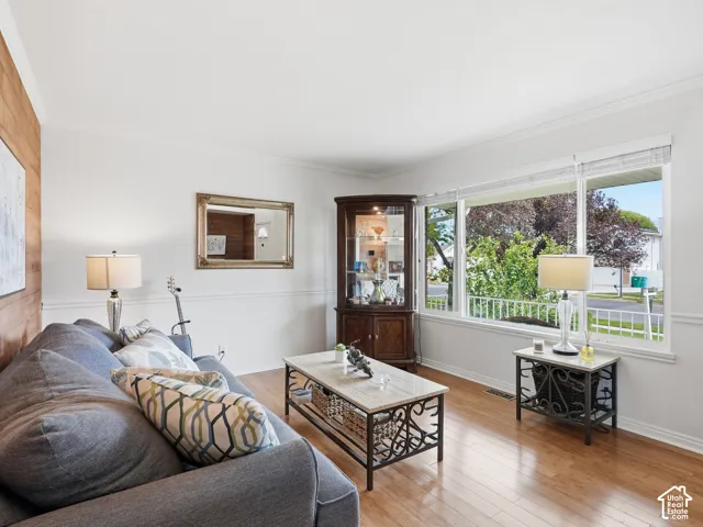 Hardwood-finish flooring, white painted walls, large picture windows, crown molding, and wainscoting