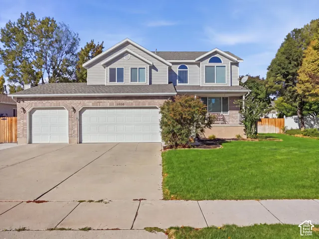 Two-story residence with a multi-pane arched window, an attached two-car garage, a separate single-car garage, a concrete driveway, and a covered front porch