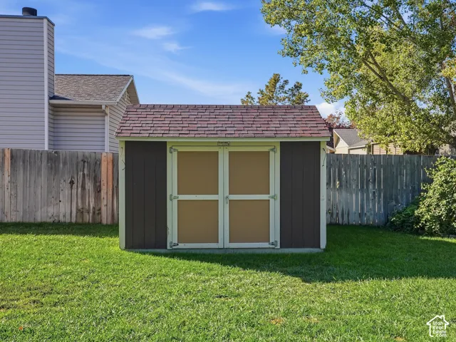 Freestanding storage shed with wood-panel siding and shingle roofing