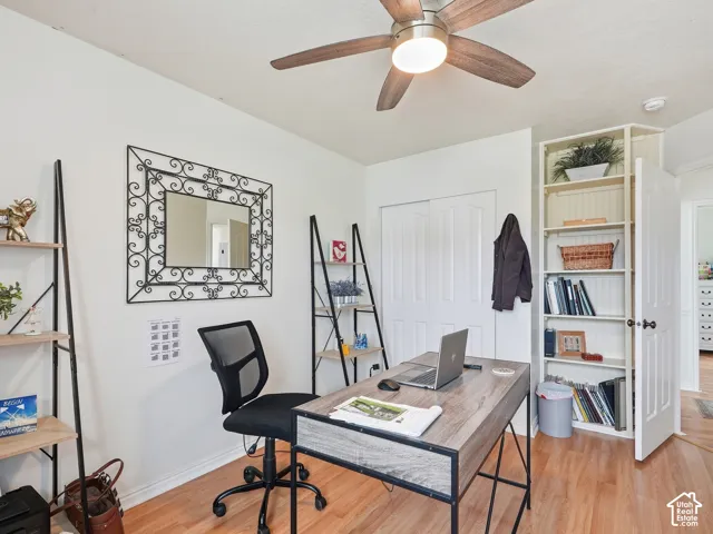Wood-finish flooring, ceiling fan with integrated lighting, built-in shelving, white paneled doors, and white walls