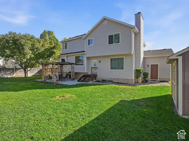 Expansive grassy yard with a wooden gazebo, concrete patio, and a storage shed