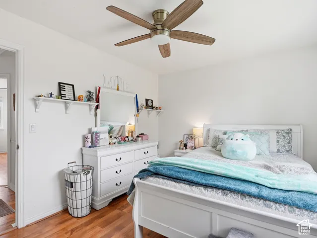 Wood-finish flooring, white walls, and a ceiling fan with light fixture