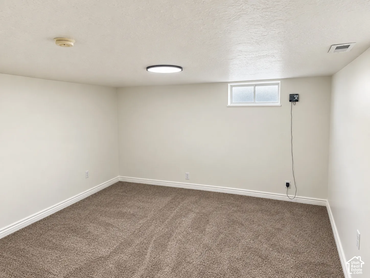 Recessed window, brown carpet flooring, white walls, and a ceiling-mounted light fixture