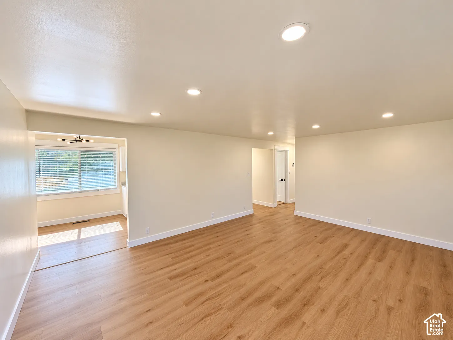 Recessed ceiling lighting, wood-finish flooring, light-colored wall paint, white trim, and a window with blinds