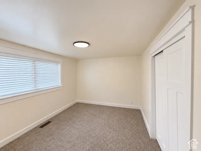Neutral-toned carpeting, white trim, and a flush-mount ceiling light