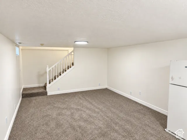 Carpeted flooring, white painted walls, white trim, white staircase with balusters, and a compact window