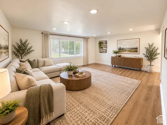 Recessed lighting, wood-finish flooring, built-in shelving, large window with blinds, and white walls