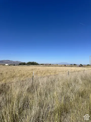Expansive open field with natural grass, perimeter fencing, and distant mountain ranges