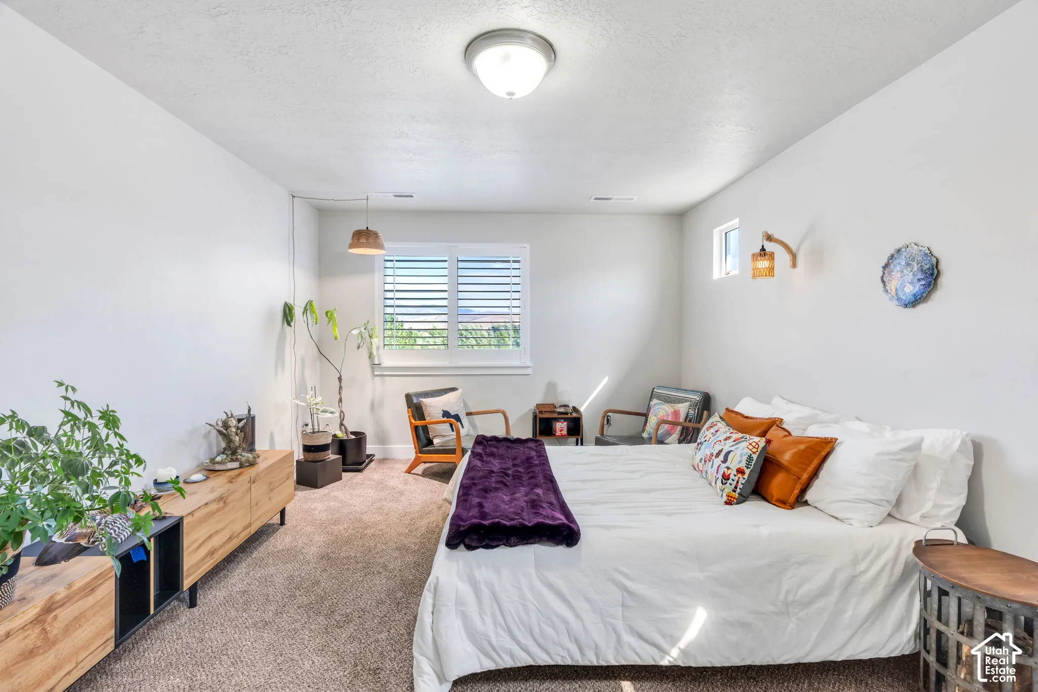 Neutral wall color, wall-to-wall carpeting, ceiling-mounted light fixture, recessed window with horizontal blinds, and a built-in wall sconce