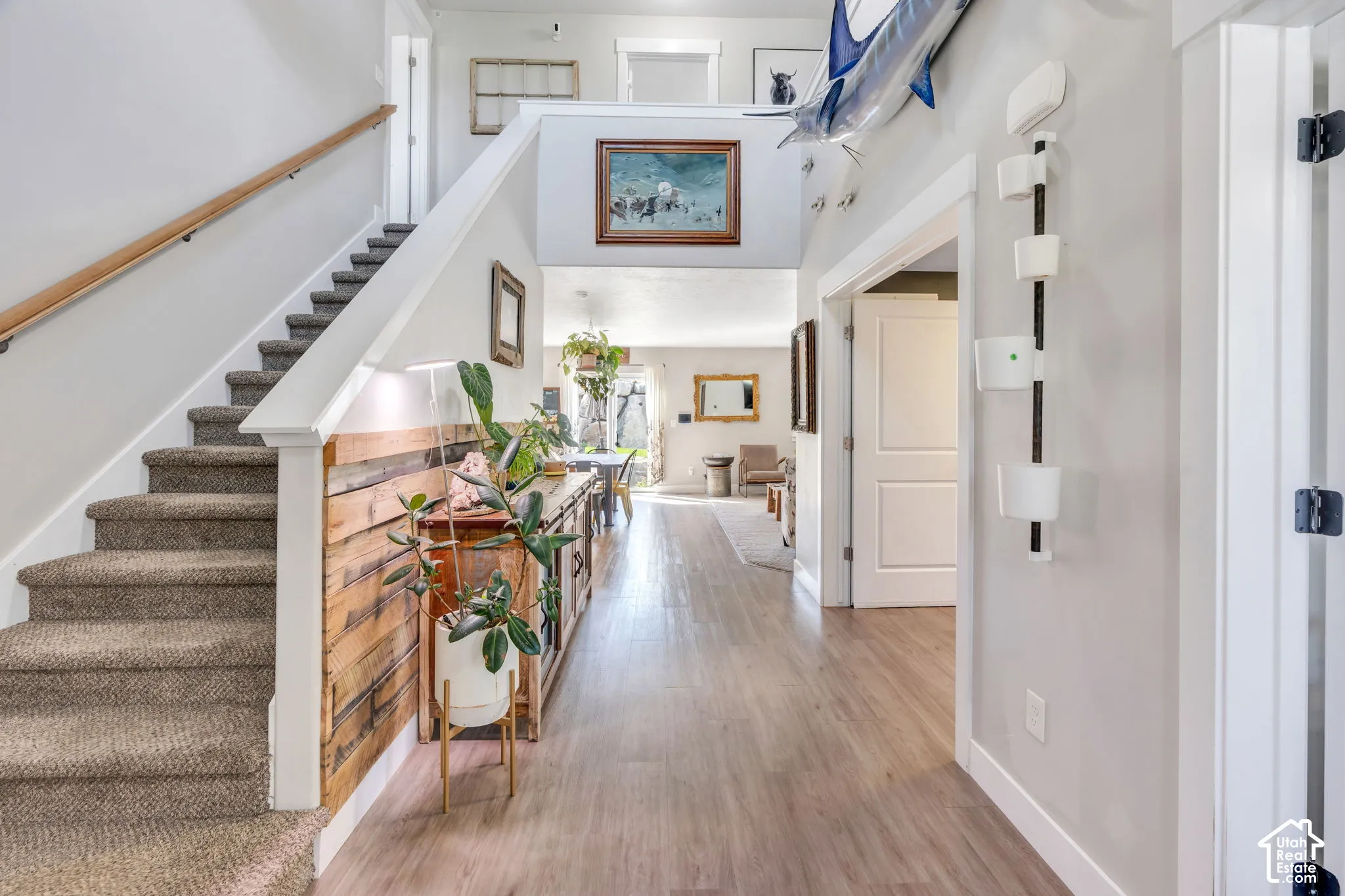 Carpeted staircase with light wood handrail, wood-finish flooring, white trim, and a prominent wood accent wall
