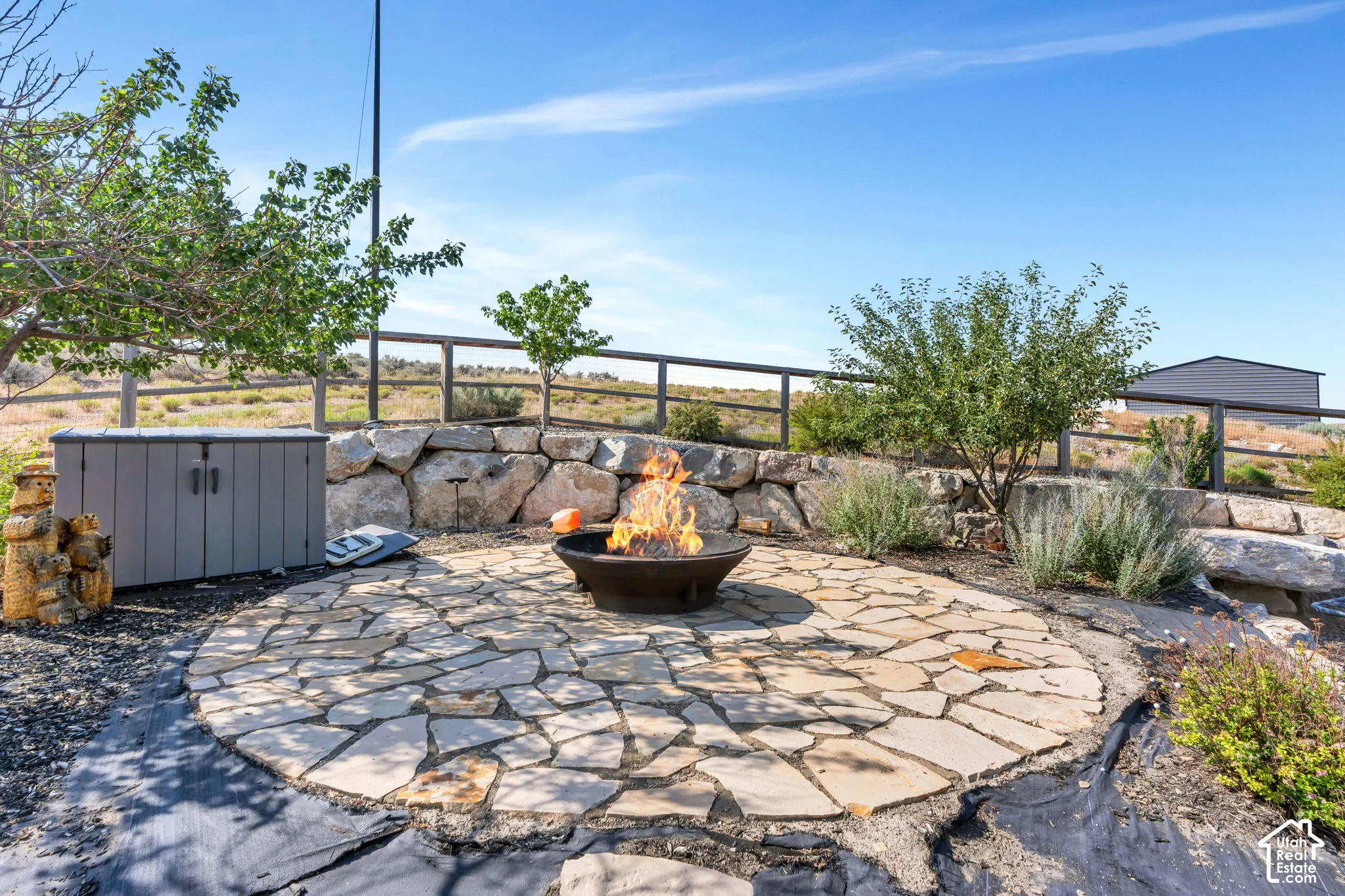 Flagstone patio with a built-in fire pit, surrounded by a rock retaining wall and mature plantings