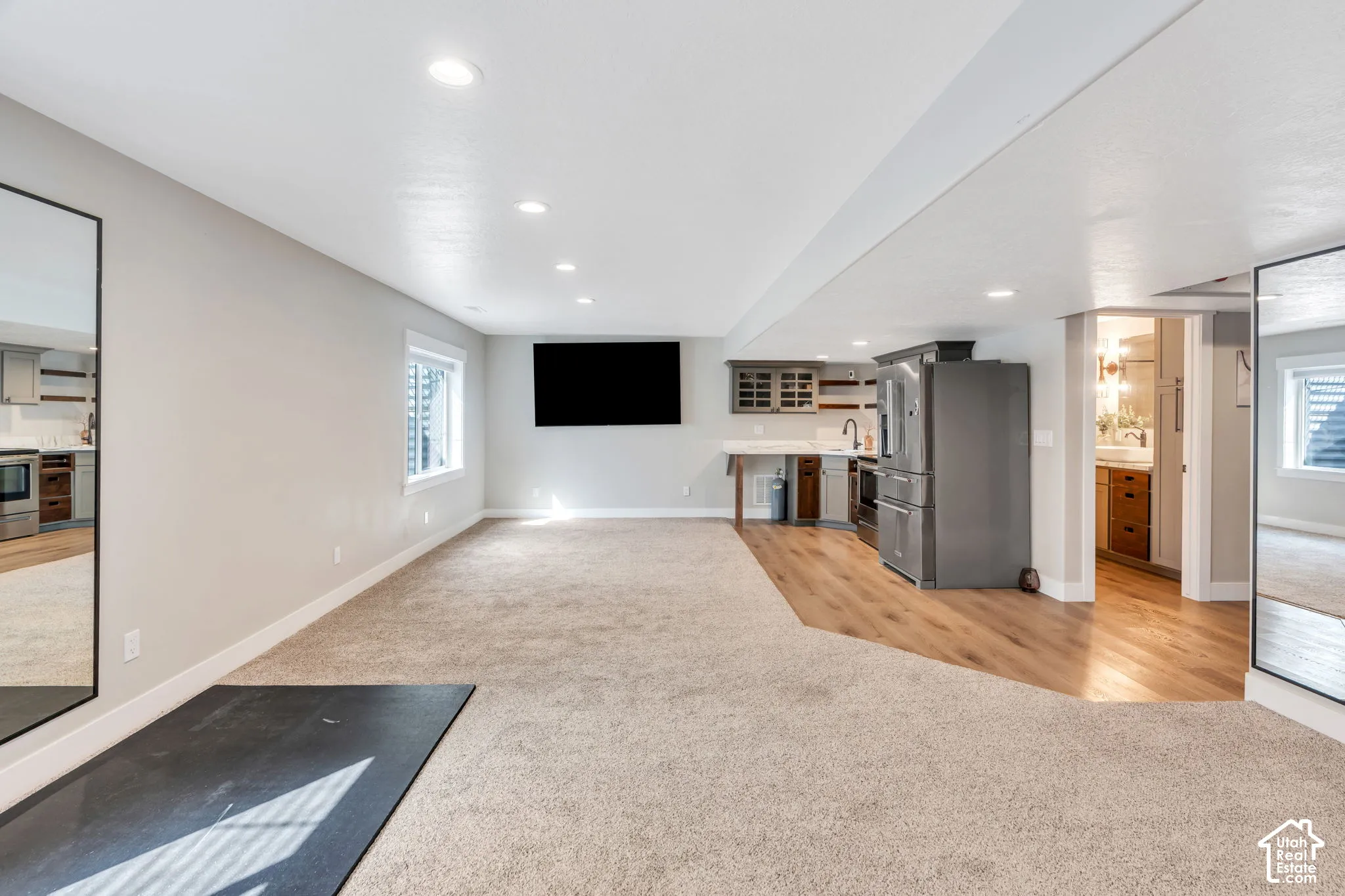 Recessed lighting, wood-finish flooring, full-size stainless steel refrigerator, window with blinds, and built-in cabinetry