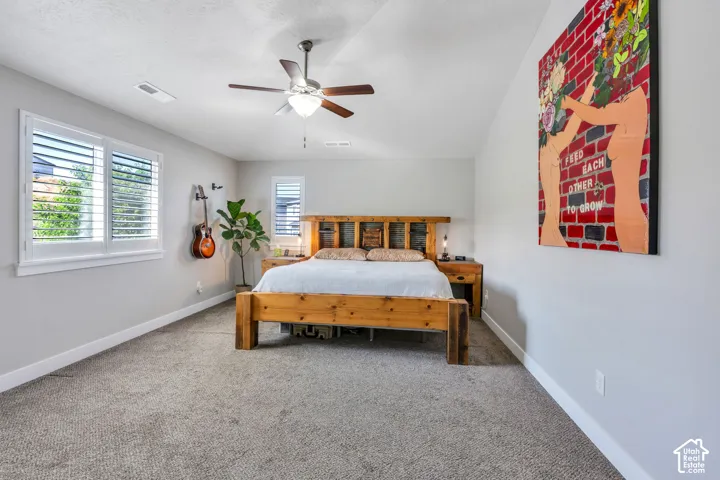 Carpeted flooring, white plantation shutters, a ceiling fan with integrated lighting, and light gray wall paint