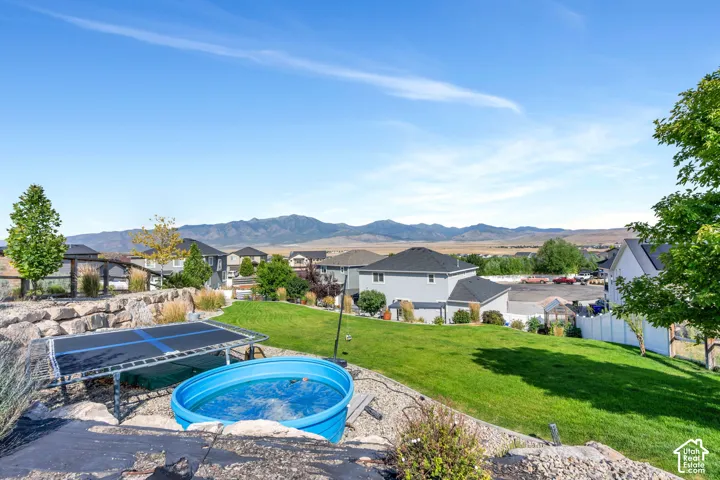Expansive sloped lawn with mature landscaping and distant mountain scenery
