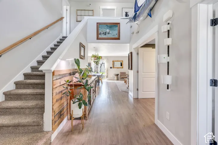 Carpeted staircase with light wood handrail, wood-finish flooring, white trim, and a prominent wood accent wall