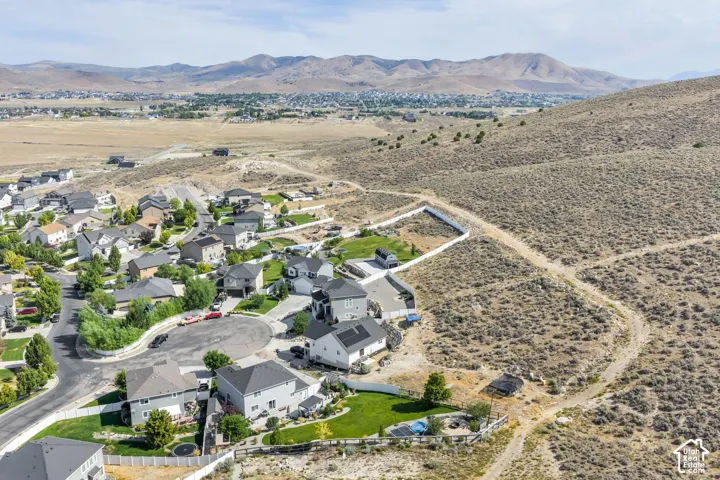 Neighborhood with paved roads and cul-de-sac designs, bordered by expansive natural terrain and distant mountains