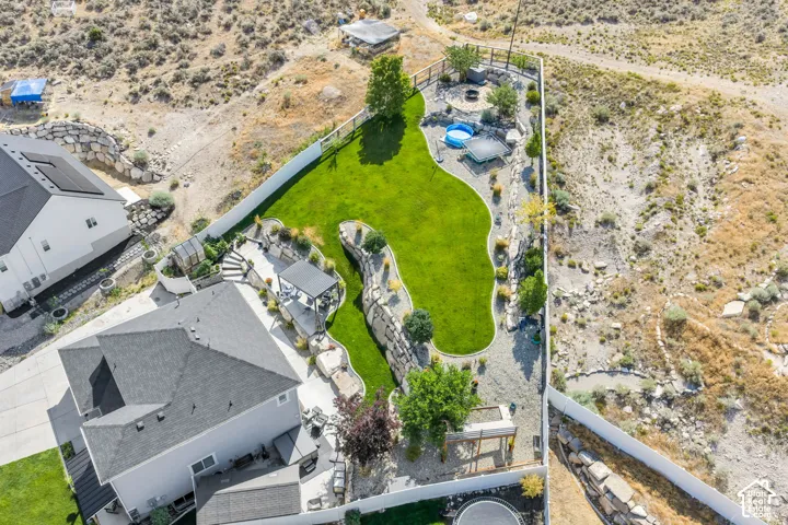 Expansive terraced yard featuring a large manicured lawn, paved patio areas, and a pergola