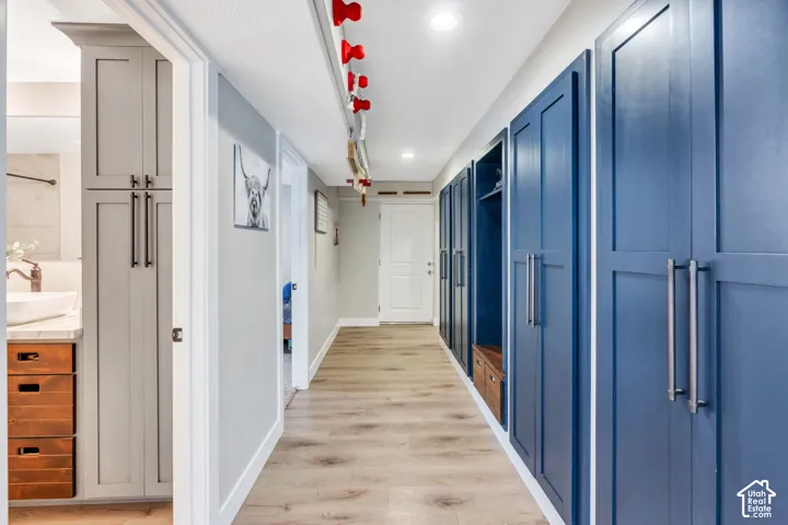 Hallway featuring extensive built-in cabinetry, recessed lighting, and wood-finish flooring